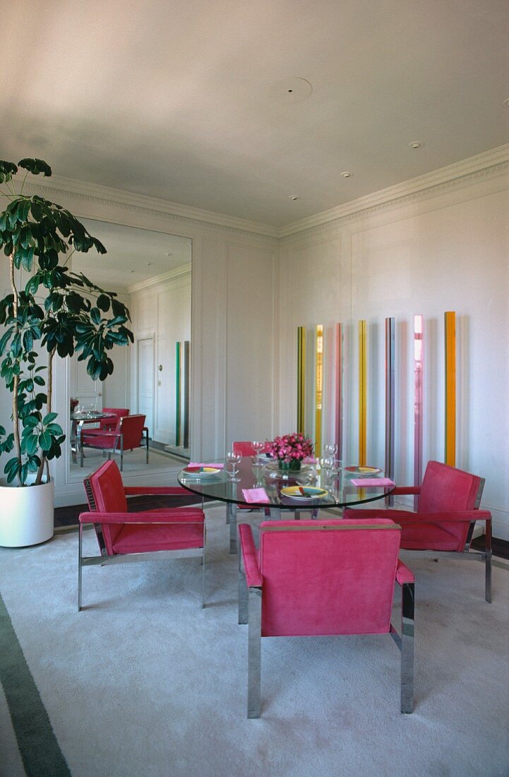 Sessel mit Stahlrahmen und pinkfarbenem Wildlederbezug um runden Glastisch in modernem 60er-Jahre-Esszimmer