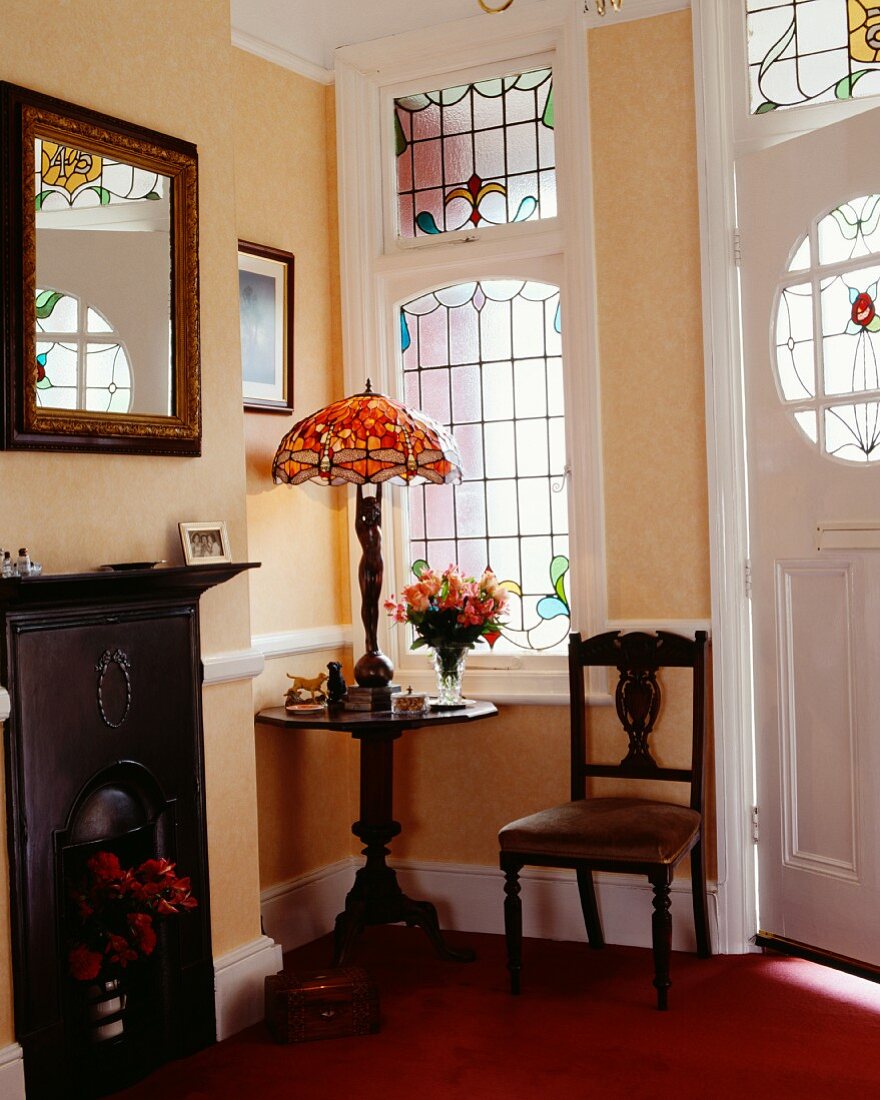 Raumecke im Stil Edward VII mit Bleiglasfenstern und Art-Nouveau-Lampe mit Bleiglasschirm auf Holztischchen