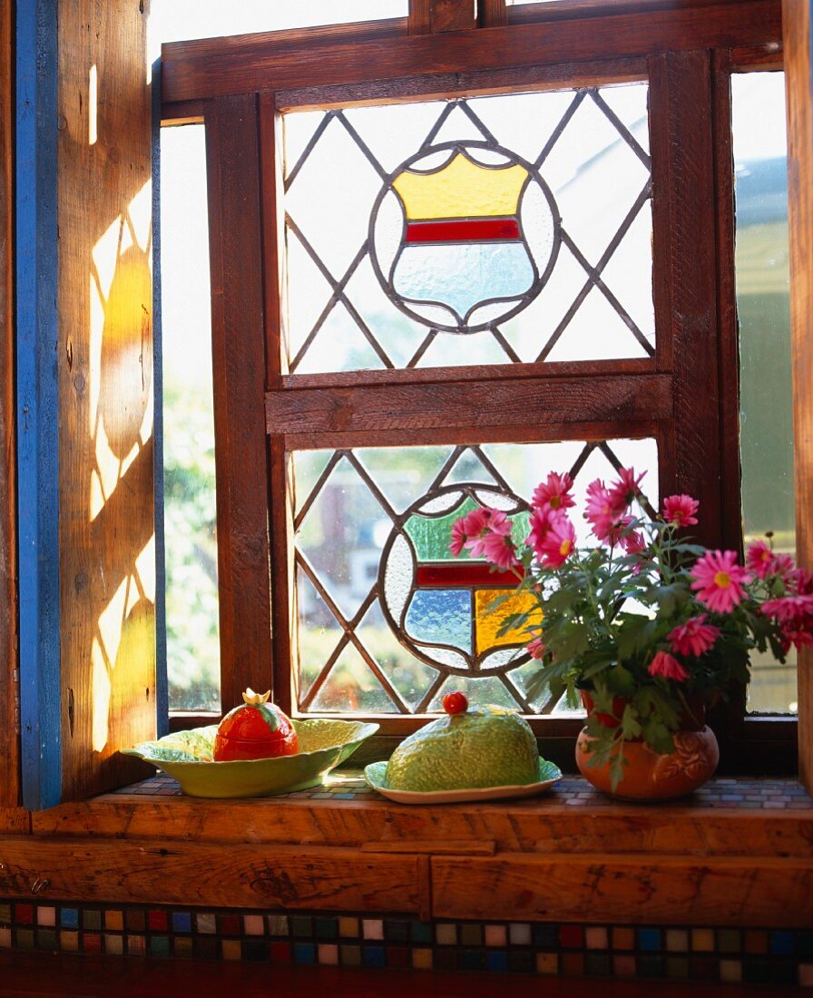 Carltonware Geschirr und Topf mit rosafarbenen Gänseblümchen auf Fensterbank unter bunten Bleiglasfenstern