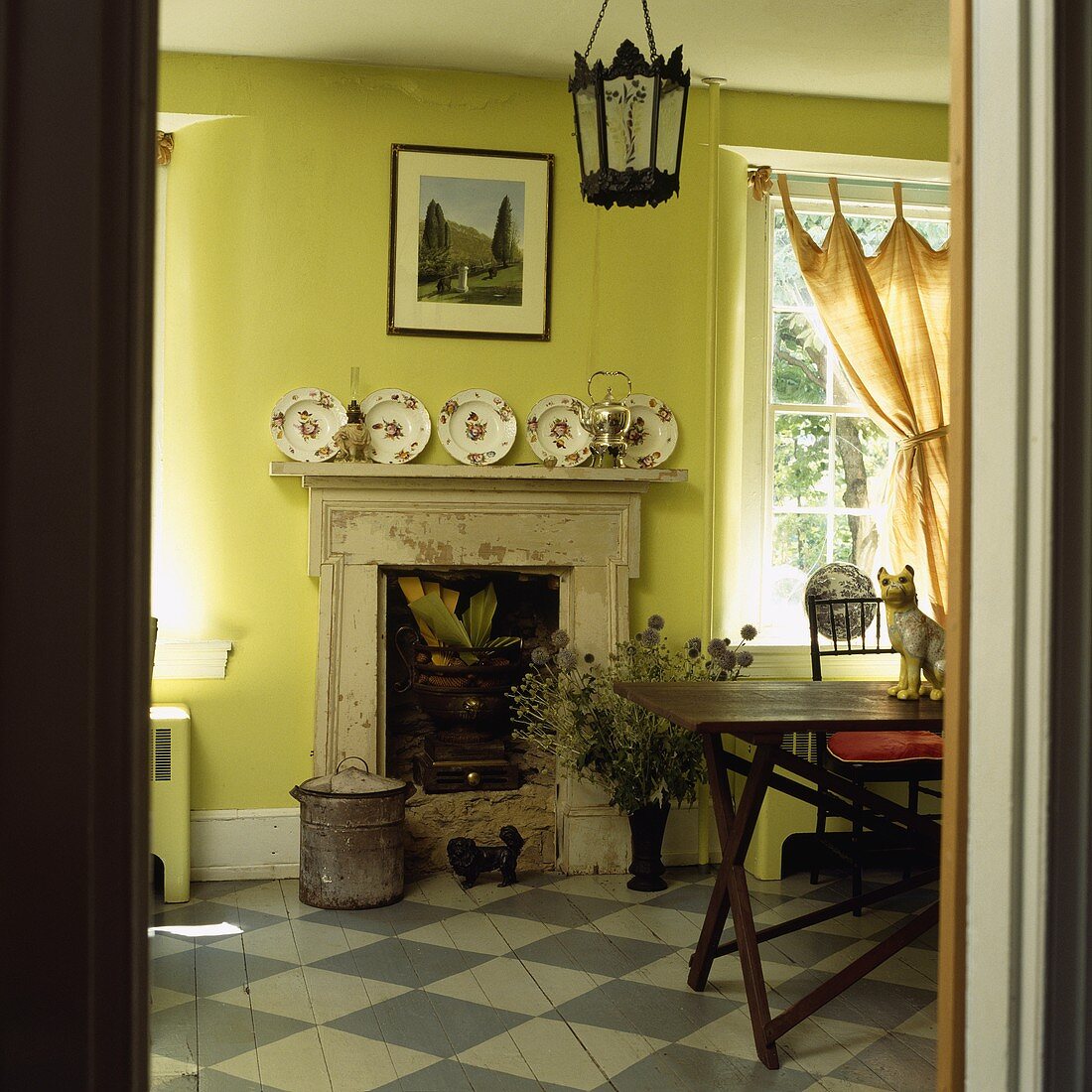 Holzboden mit grau-weißem Schachbrettmuster in einem lindgrünen Esszimmer mit Kamin