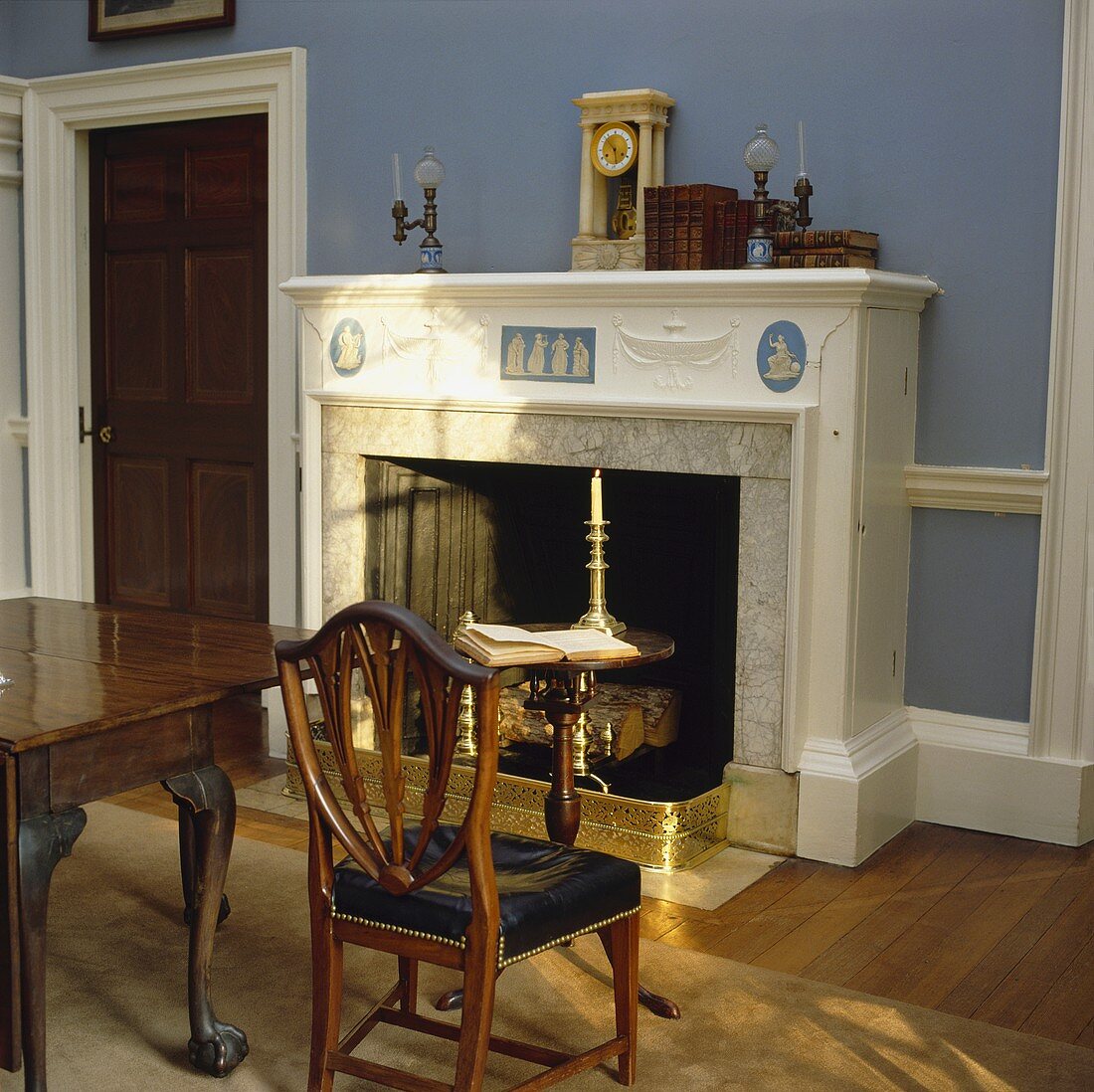 Ein Wedgewood-Kamin und antike Möbel in einem Esszimmer mit blauen Wänden