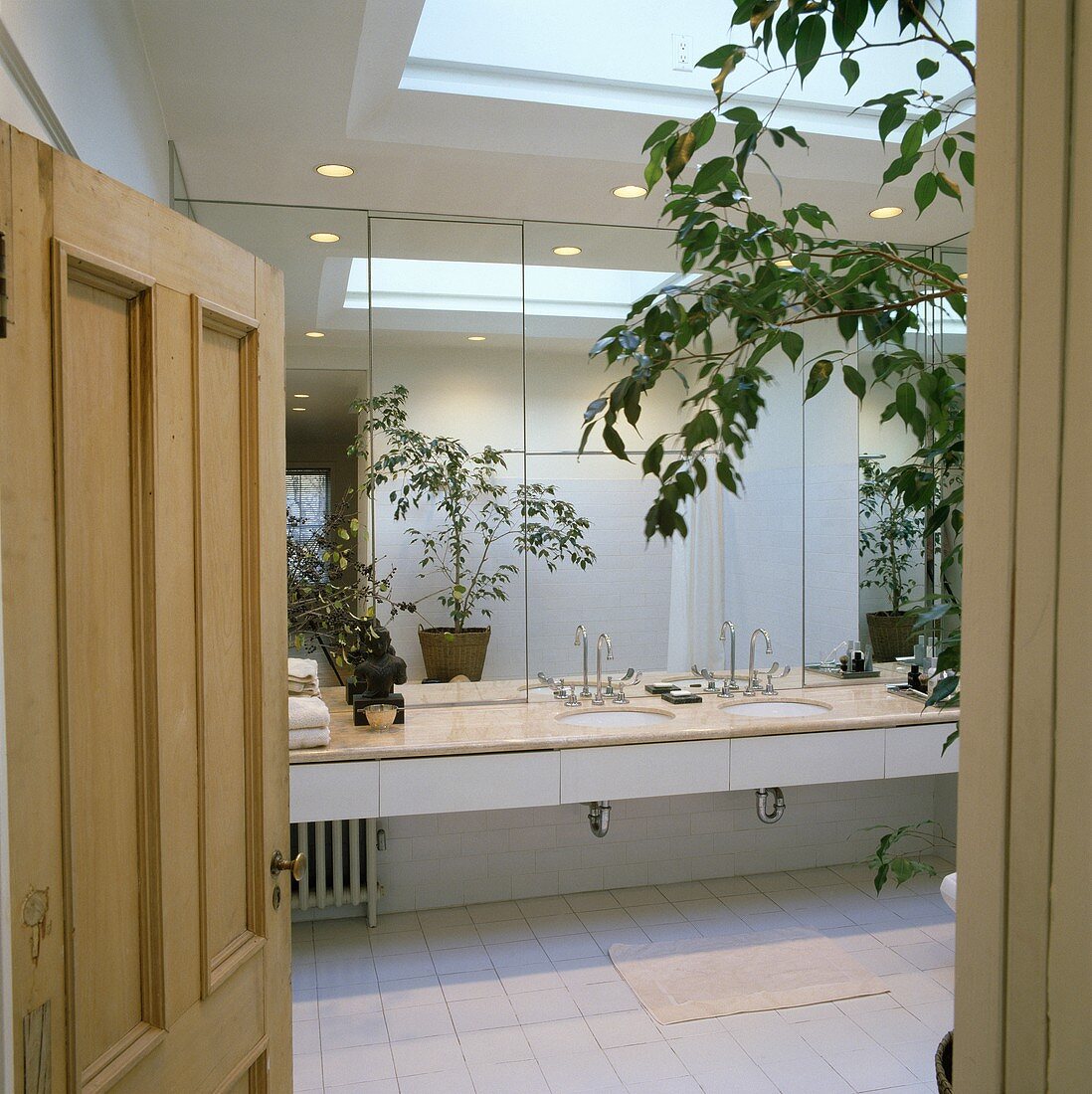 Modernes, weissgefliestes Loft-Badezimmer mit Spiegelwand, Doppelwaschbecken und Oberlicht