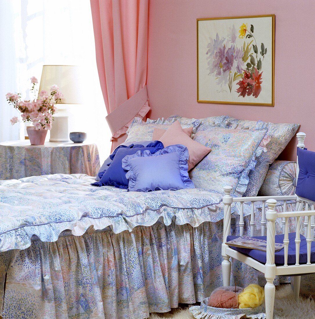 Schlafzimmer mit abstrakt gemusteter Bettdecke in Rosa und Blau, dazu passende Kissen in Rosa und Blau und einem pinkfarbenem Vorhang