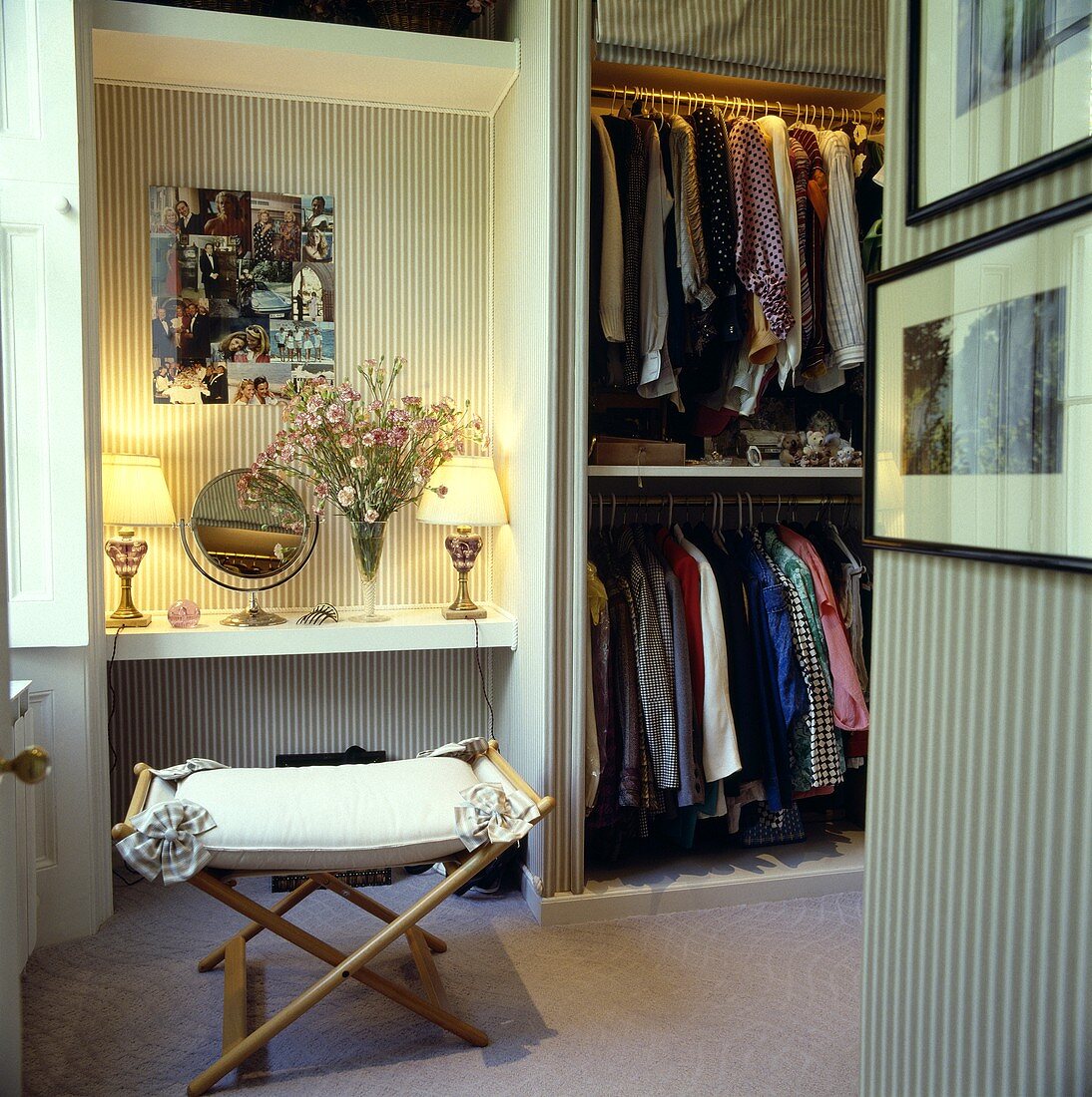 Männliches Ankleidezimmer mit gestreifter Tapete, offenem Kleiderschrank, Regal mit brennenden Tischlampen und einem Hocker