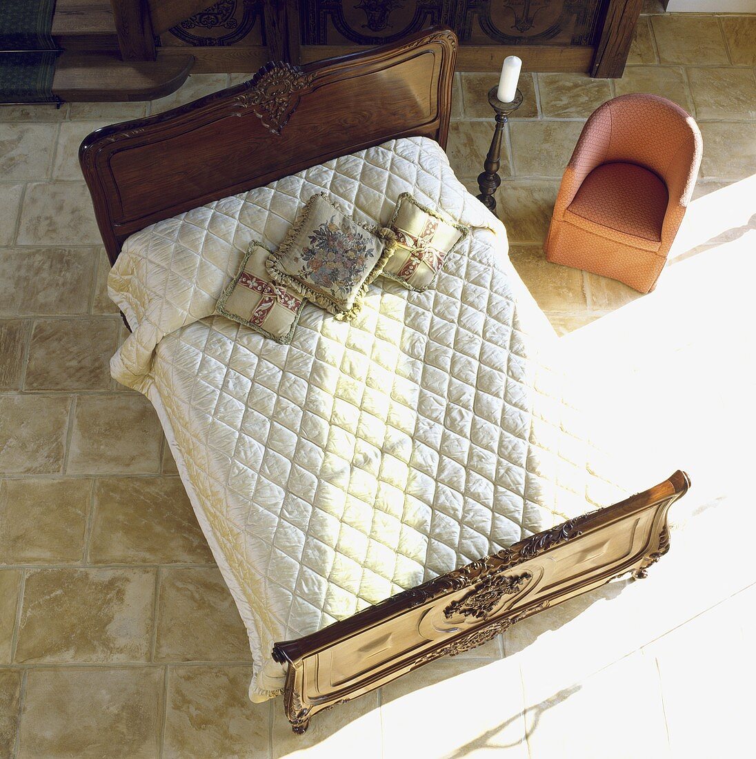 Blick von oben auf ein Doppelbett mit cremefarbener Tagesdecke in einem Möbelhaus