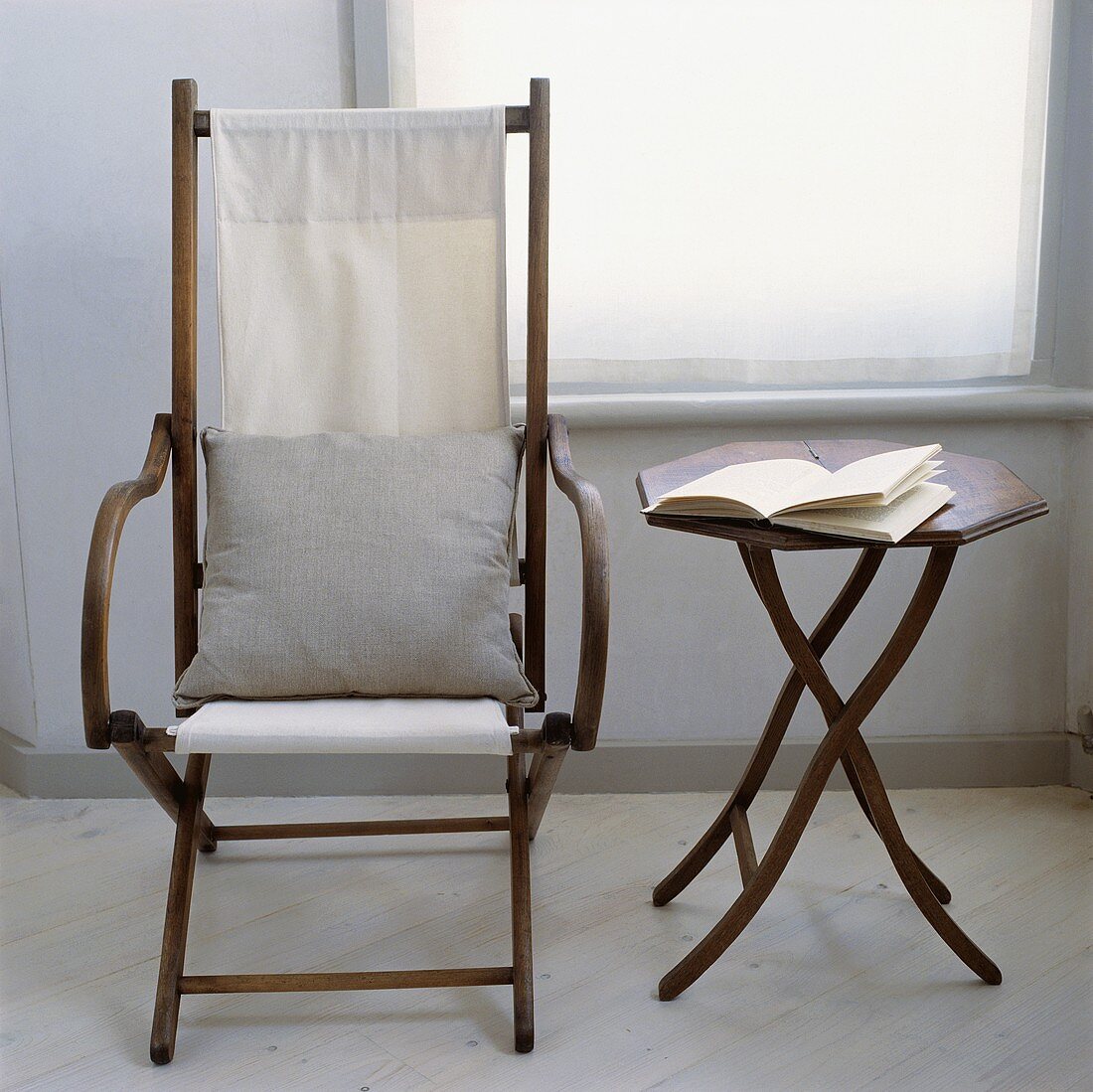 Antique Campaign-Stuhl mit weißem Kissen neben einem kleinen achteckigen Tisch