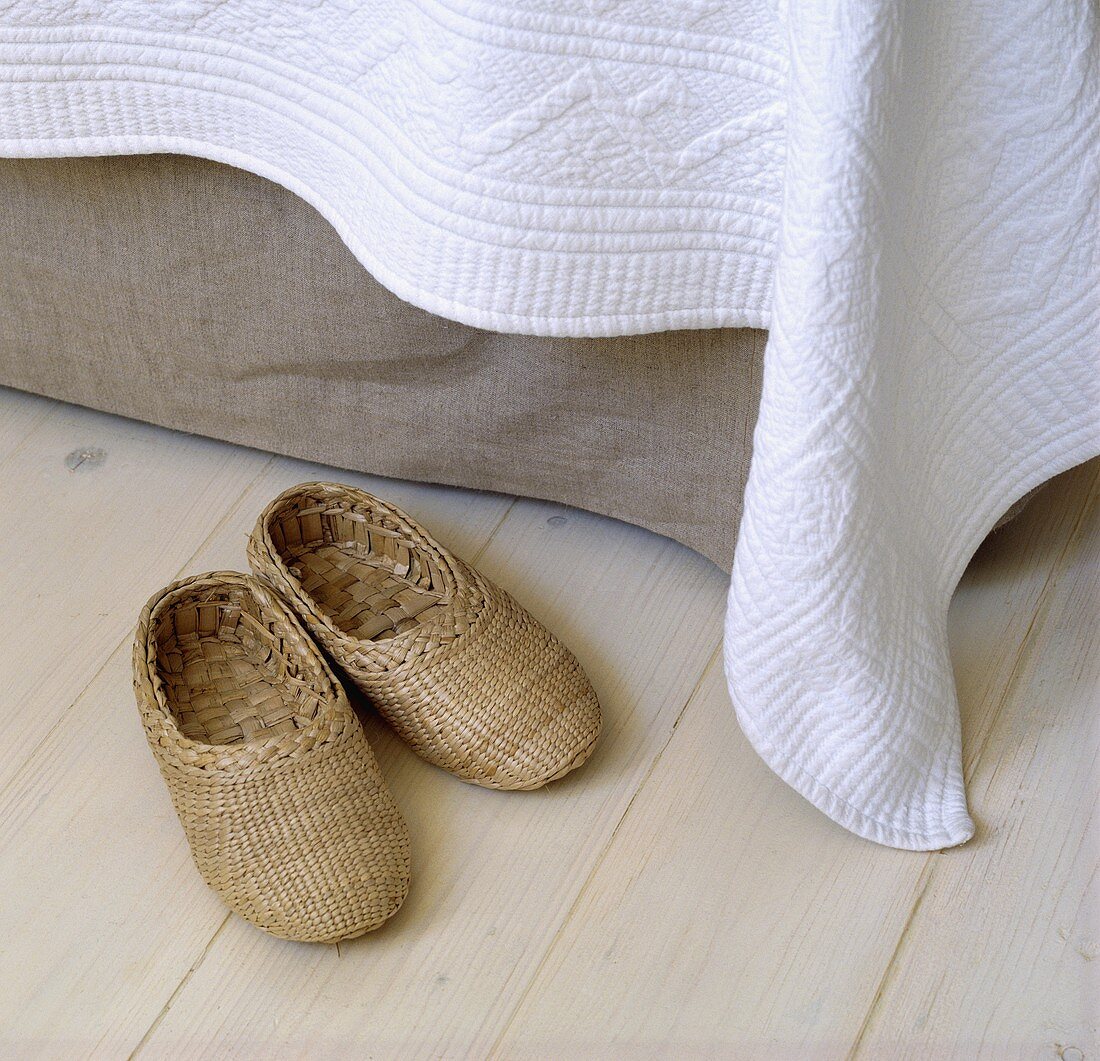 Pantoffeln aus Seegras neben einem Bett