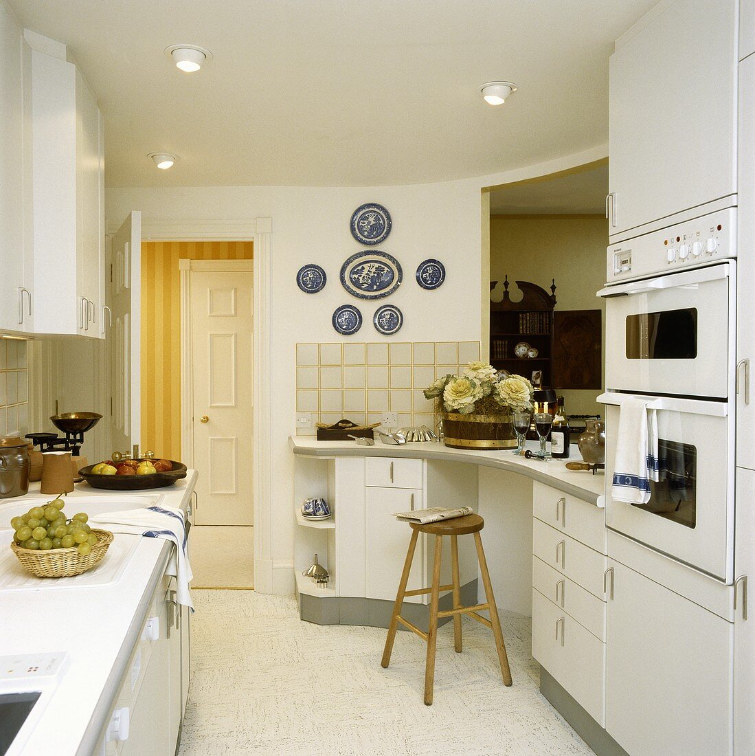 weiße Küche mit Einbaugeräten und einer Frühstücksbar