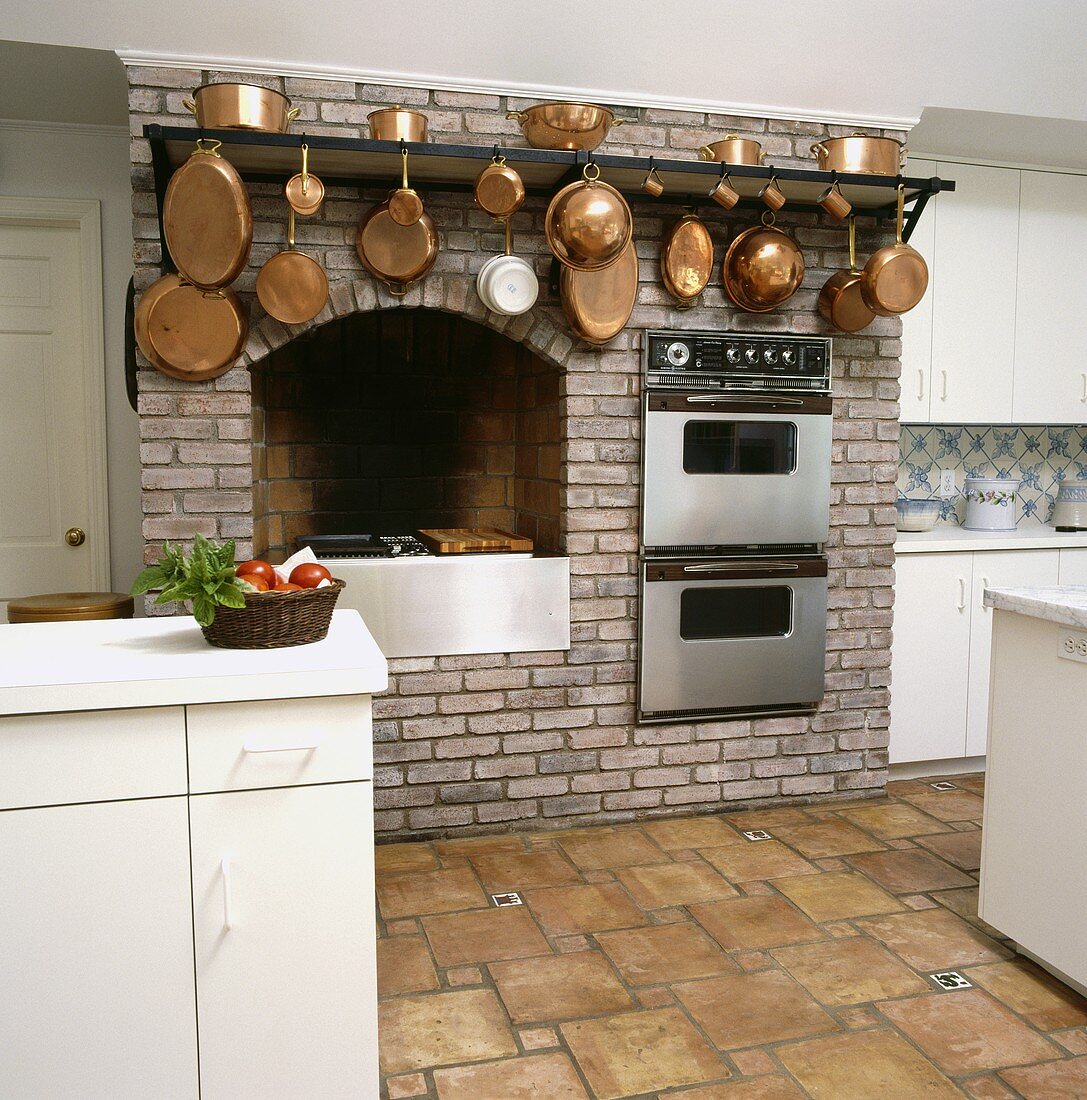 Backsteinmauer mit Einbaugeräten und Kupferpfannen in einer Küche