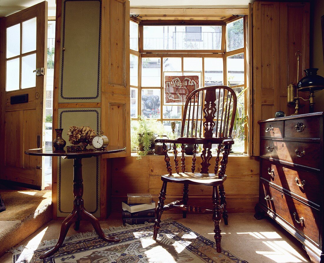 Antiker Windsor-Stuhl, ein viktorianischer Tisch und eine Kommode vor dem Fenster