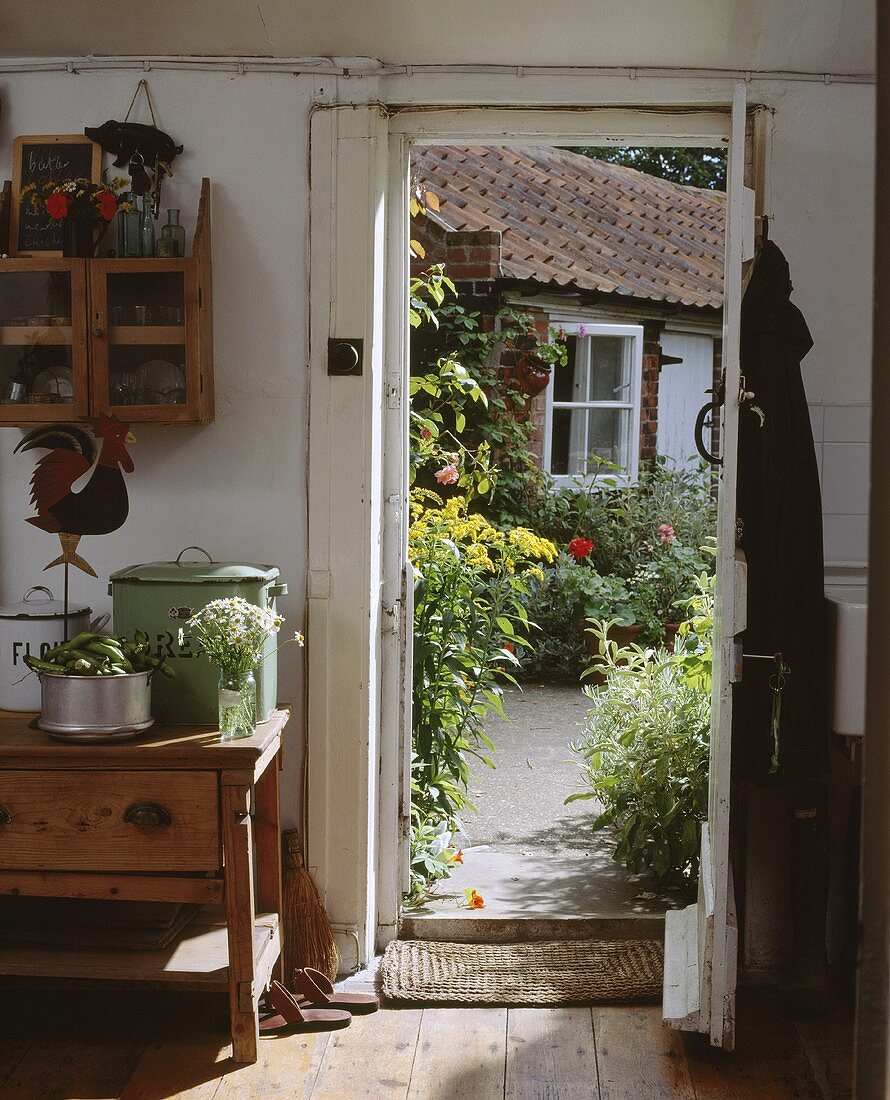 Blick aus dem kleinen Landhaus durch die geöffnete Tür auf den Garten