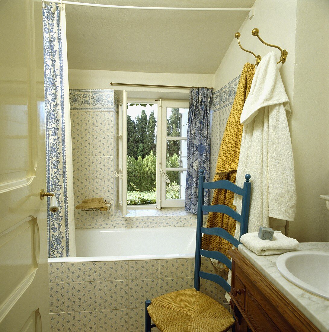 Ländliches Badezimmer mit blau-weissen Fliesen und einem Ladderback-Stuhl