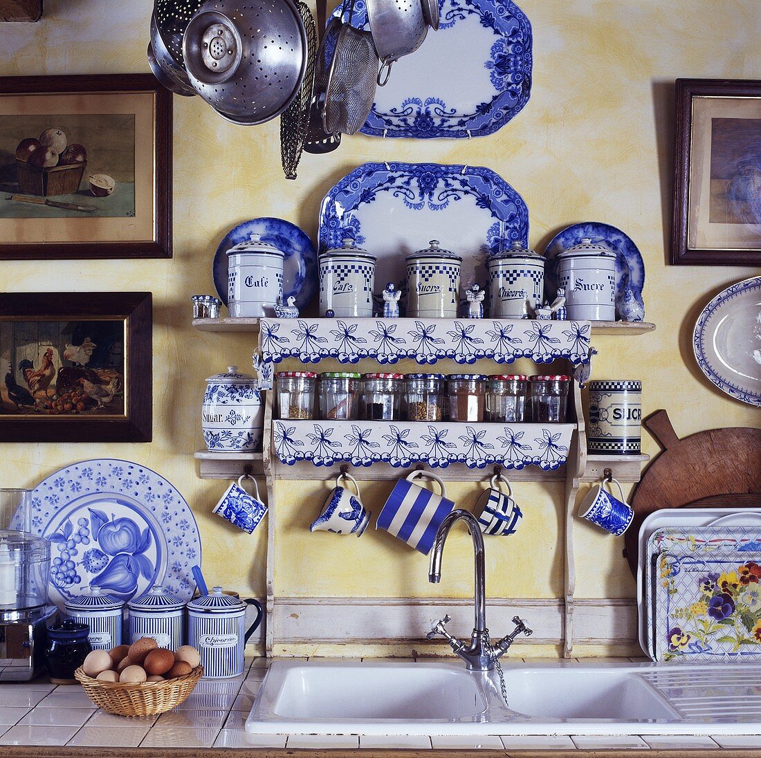 Gewürzregal und blau-weisses Geschirr über dem Spülbecken in einer Küche