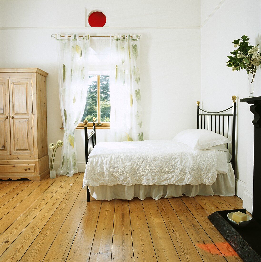 Grosses weisses Schlafzimmer mit Holzdielen und einem Bett mit weisser Bettwäsche