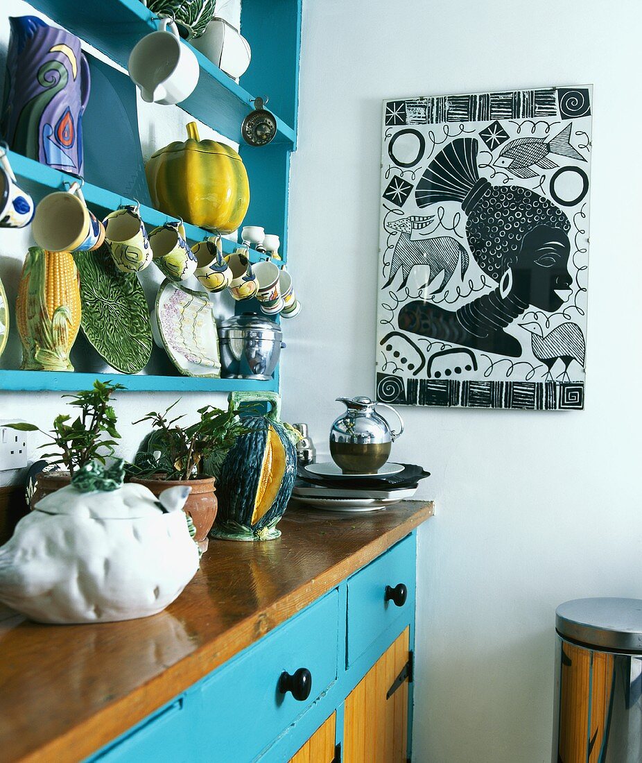 Keramik mit Gemüsemotiven am Regal hängend über Küchenschrank mit türkisfarbenen Schubladen im südländischem Flair