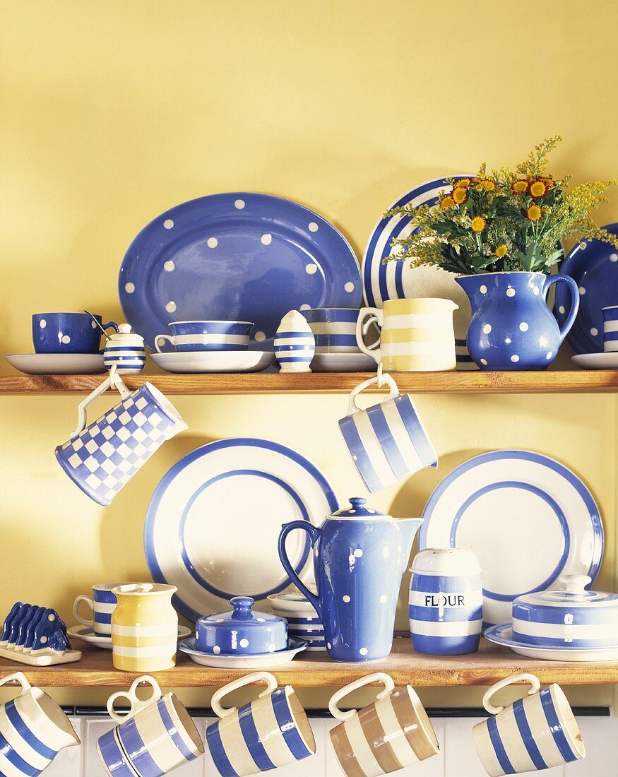 Weiß blaues Keramikservice auf Küchenregal vor gelb getönter Wand