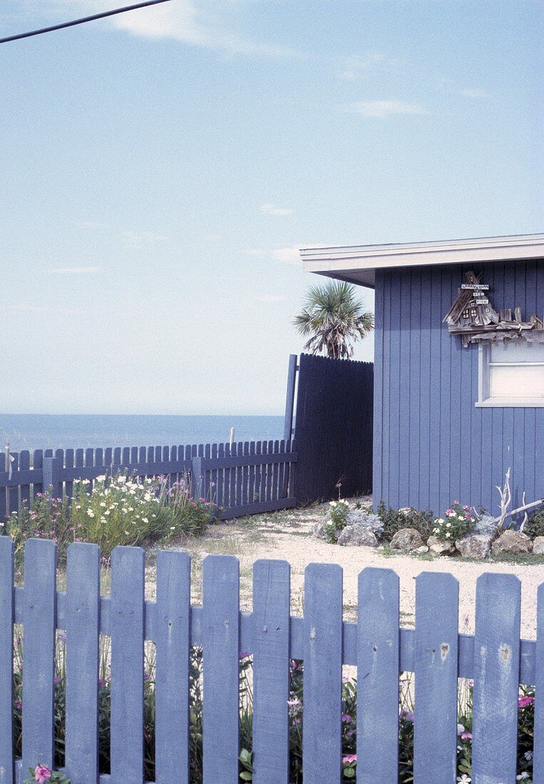 Blaues Holzhäuschen mit blauem Zaun am Meer an der Ostküste der USA