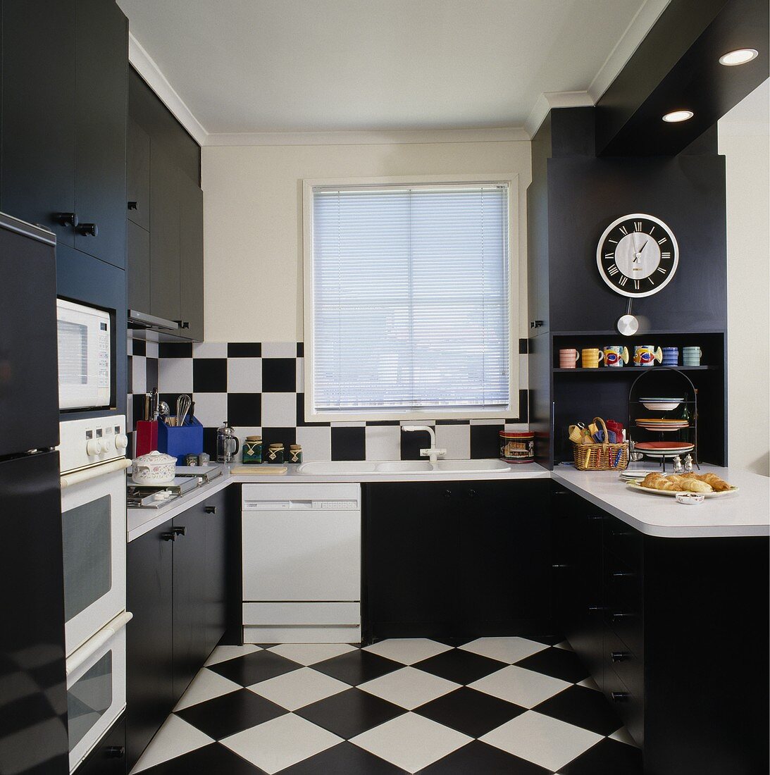 Schwarz-weiße Wand- und Bodenfliesen in Schachbrettmuster, schwarze Küchenschränke und weiße Küchengeräte