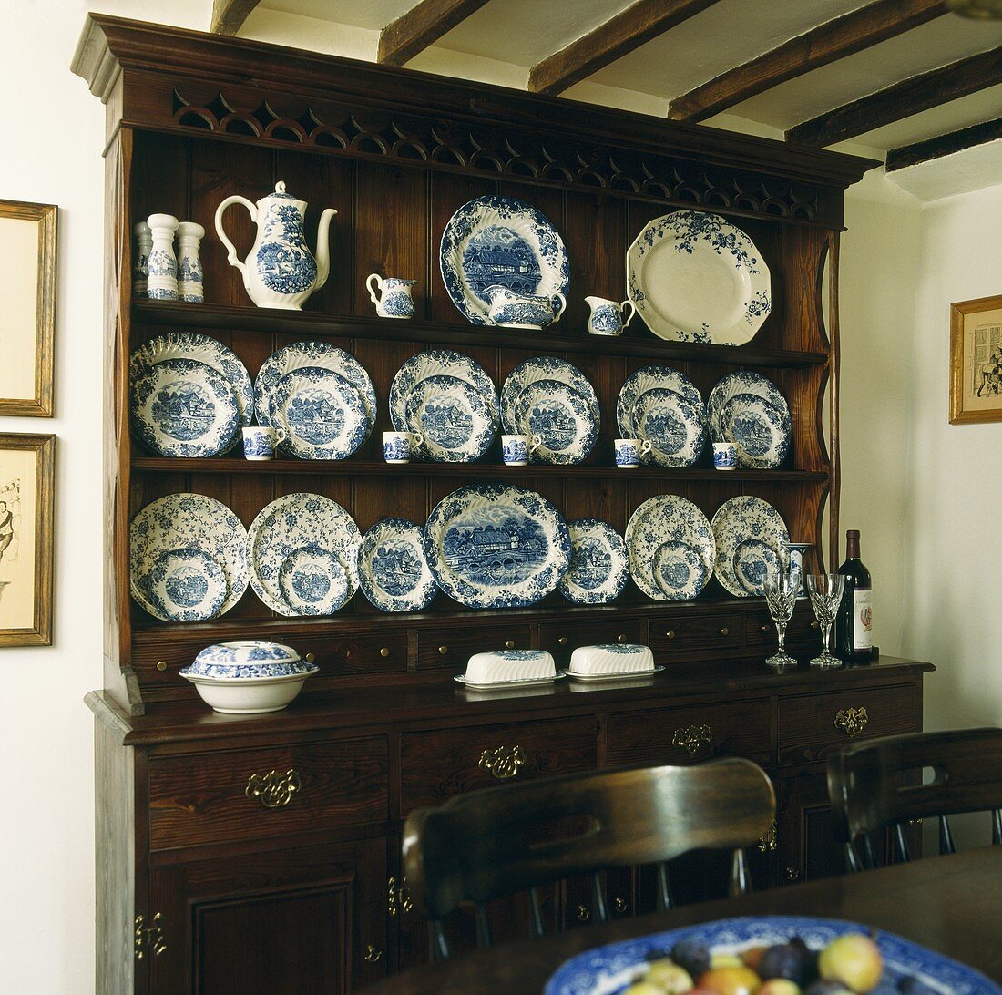 Antiker Geschirrschrank aus dunklem Holz mit blau weißem Porzellan im Landhaus-Esszimmer