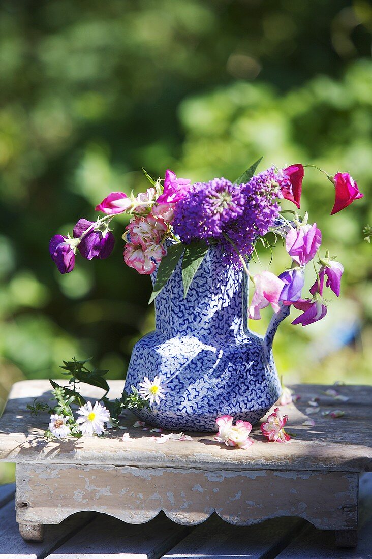 Sommerblumen in blau gemusterter Kanne auf Vintage Holzablage