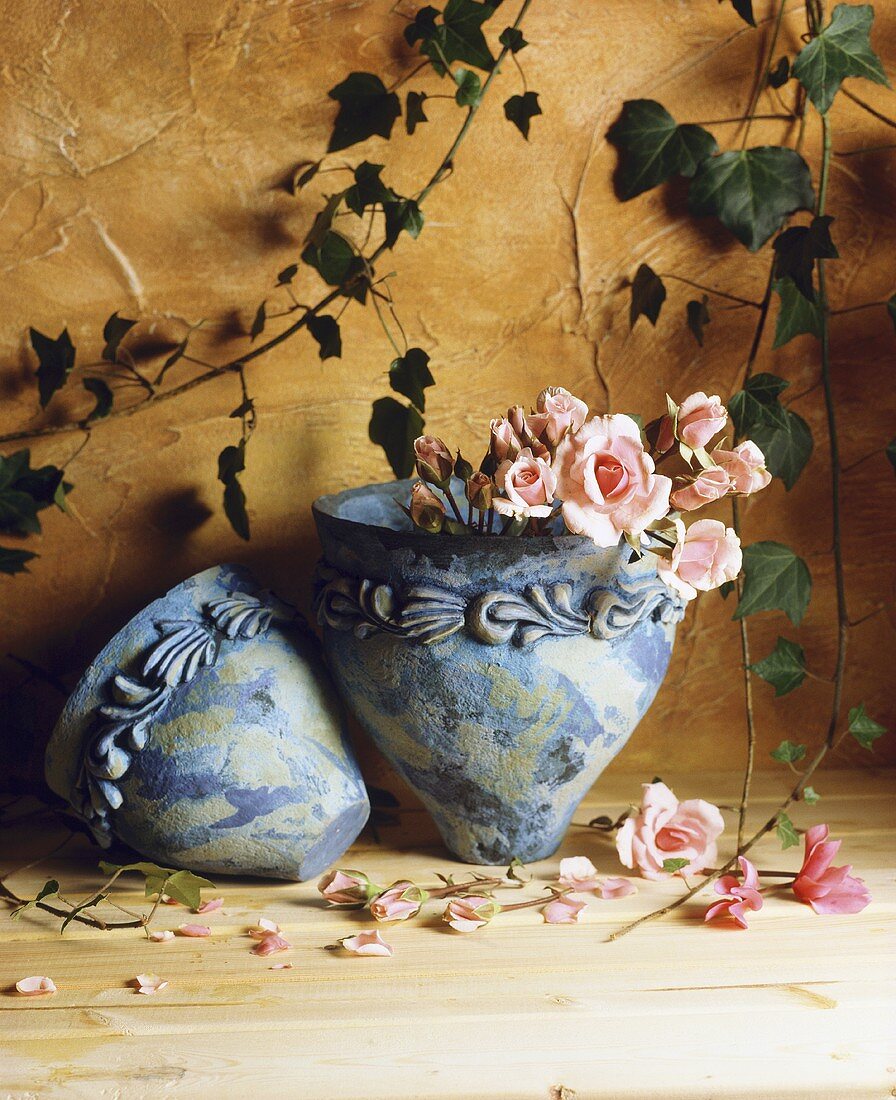 Rosa Rosen im Keramiktopf vor gelber Wand