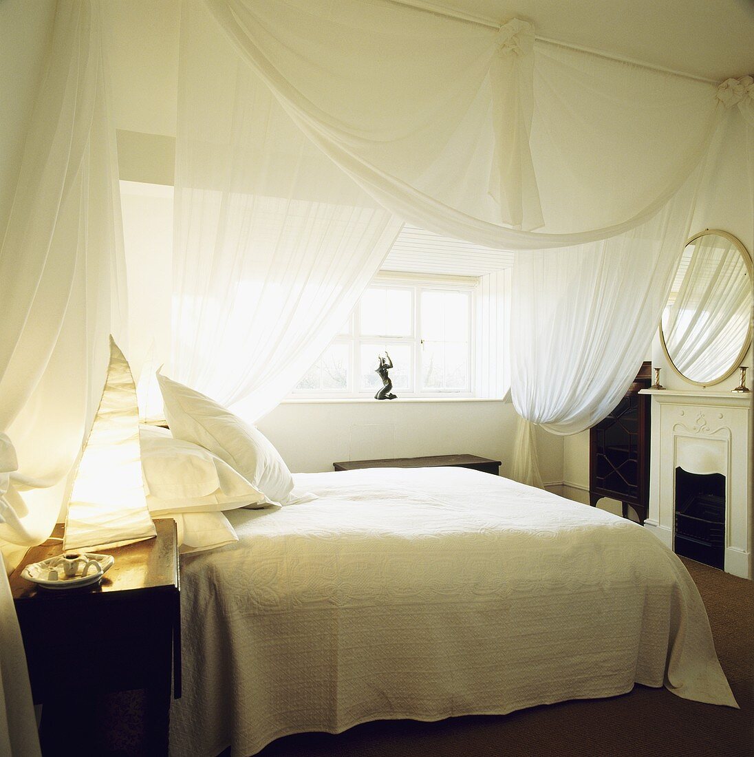 Weißes Schlafzimmer mit Moskitonetz über Doppelbett