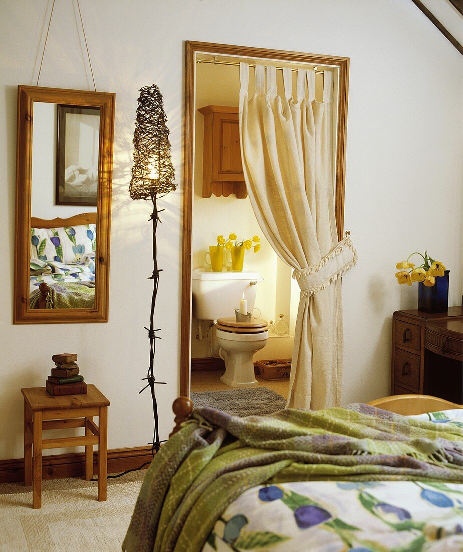 Schlafzimmer mit selbstgemachter Stehlampe neben Spiegel und Tür zum Bad ensuite