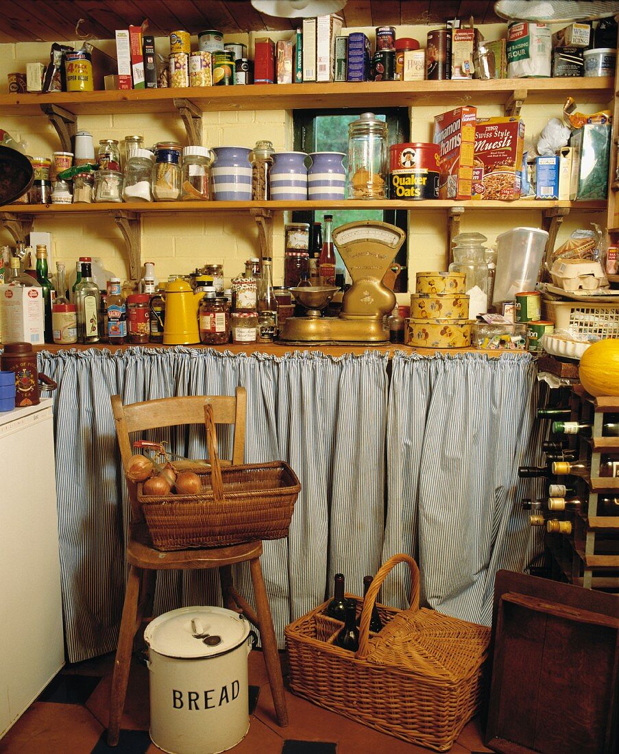 Alte Speisekammer mit Vorratsdosen in Holzregalen und Körben mit Lebensmitteln