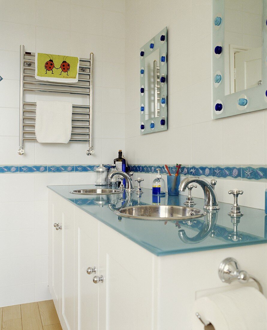 Modernes Badezimmer mit blauer Glasplatte auf Waschtisch und Wandspiegeln