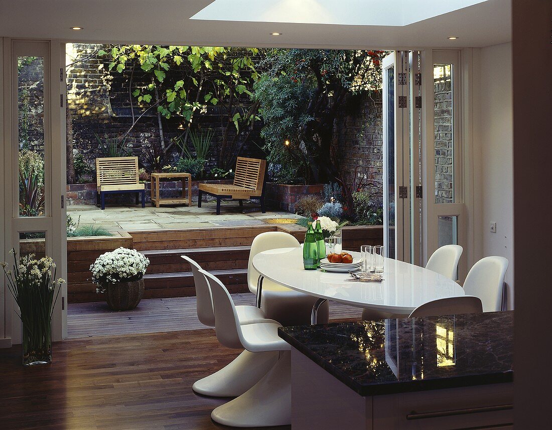 Weisser Esstisch mit Schalenstühlen vor offenen Terrassentüren