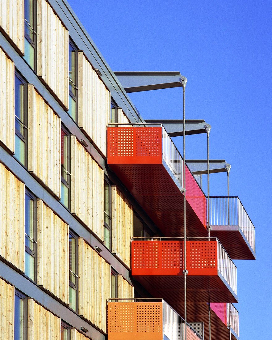 A modern apartment block with coloured balconies and sliding wooden elements
