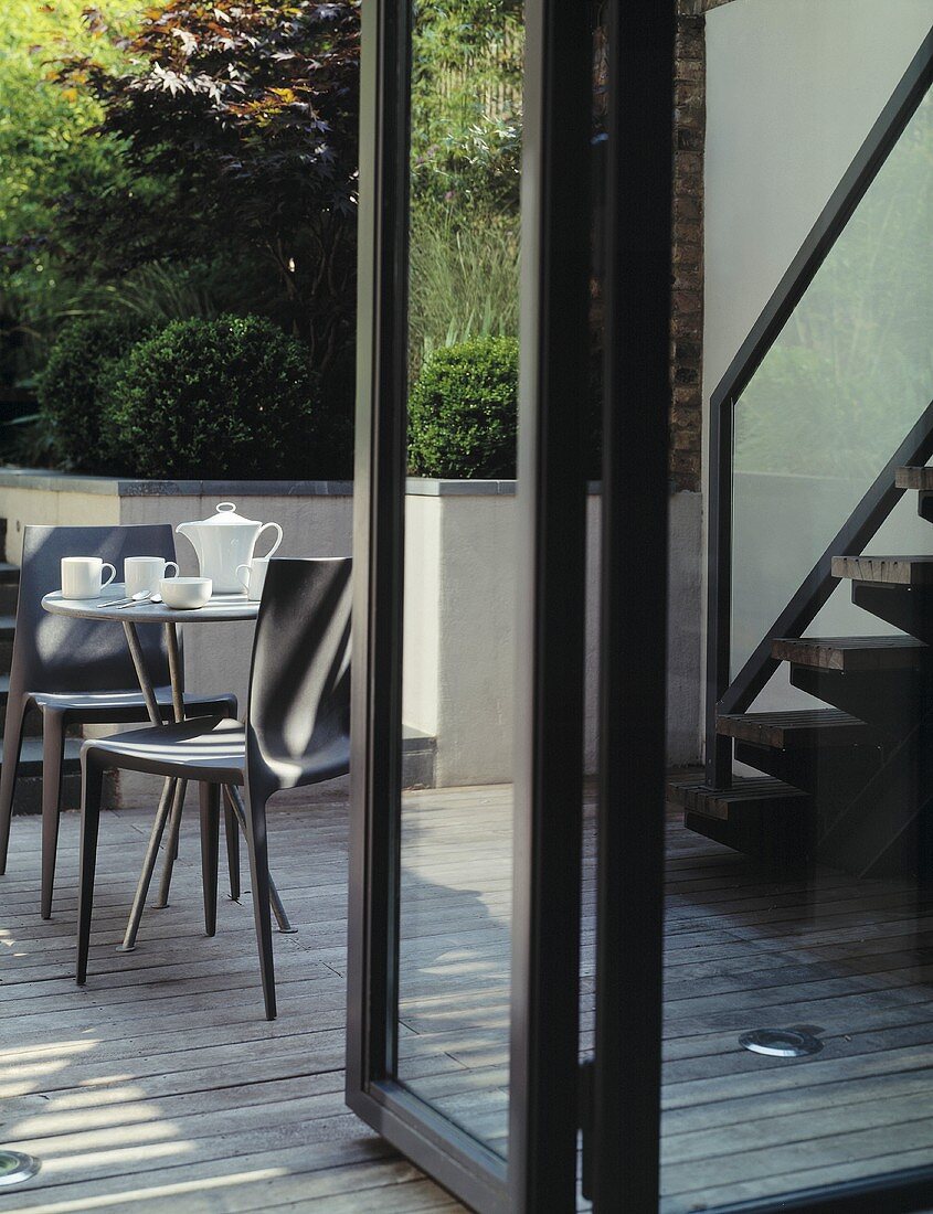 Blick durch offene Terrassentür auf Tisch mit Kaffeekanne und Tassen