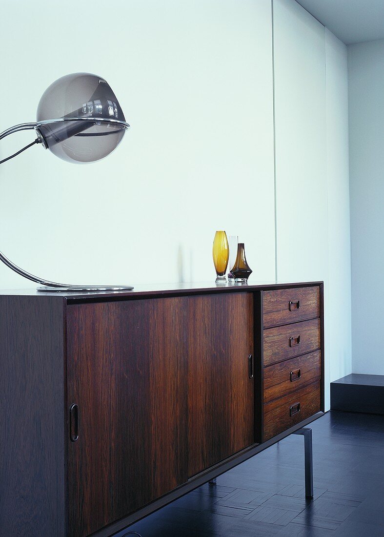 A sideboard dating from the late 1960s with a designer lamp