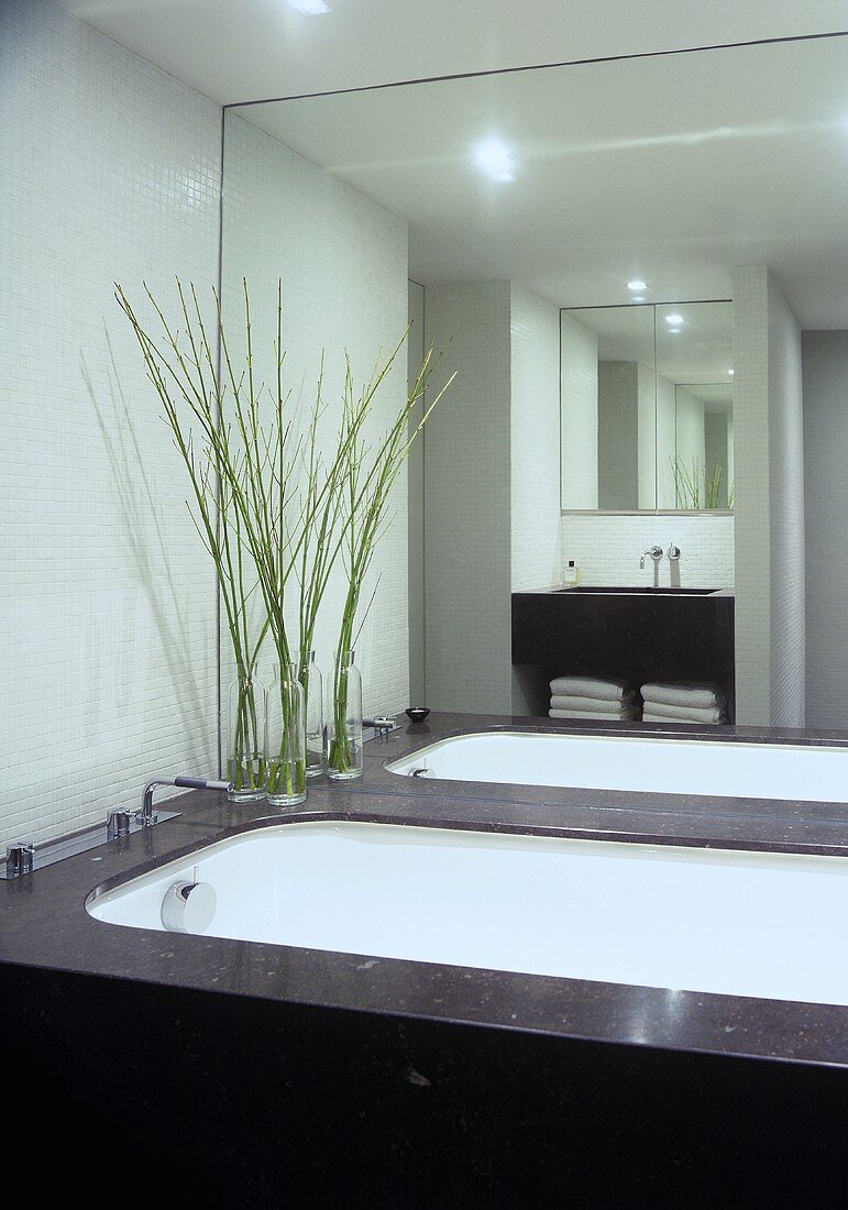 A bathroom with white mosaic wall tiles and a counter top made of Belgian granite
