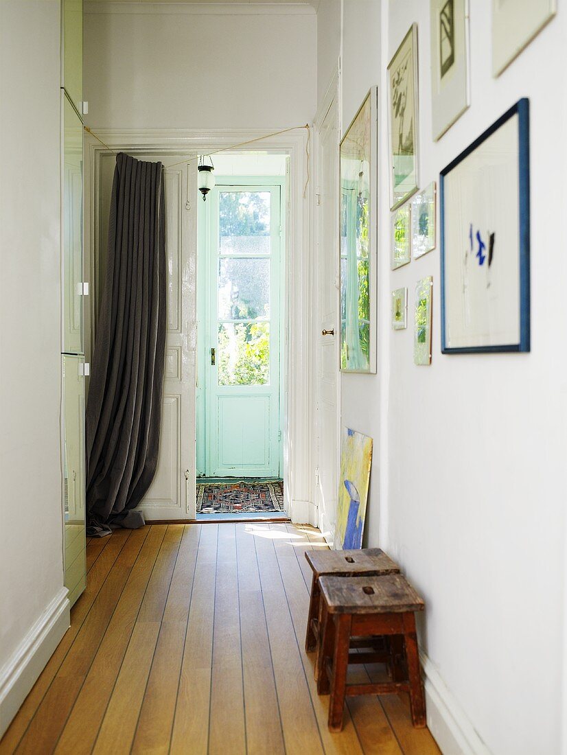 A hallway with wooden floor boards and a curtain in front of the front door of a Swedish house