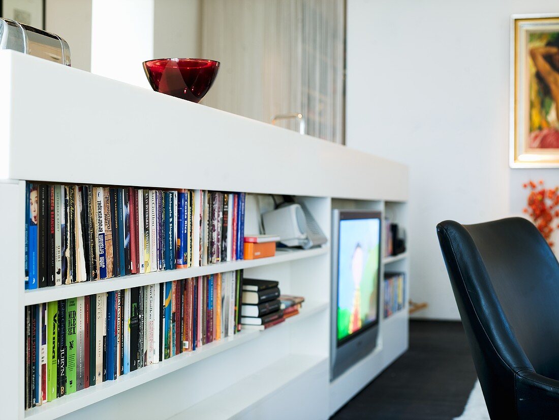 A white shelf for books and the television