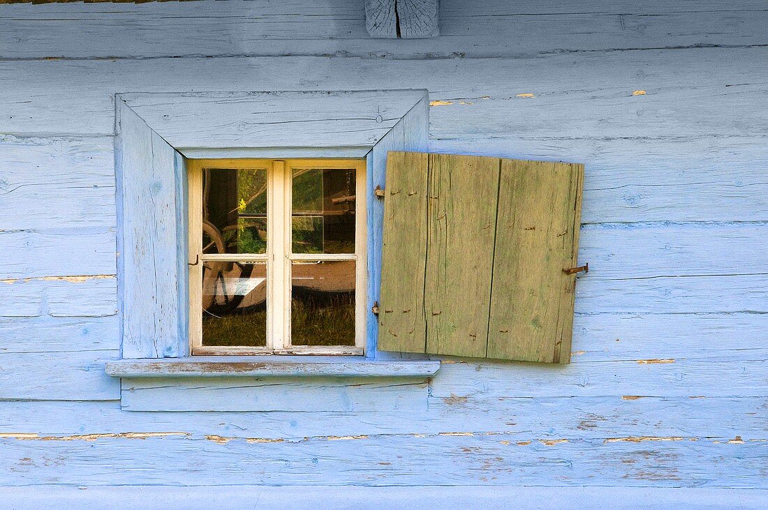 A blue wooden hut with an open window shutter