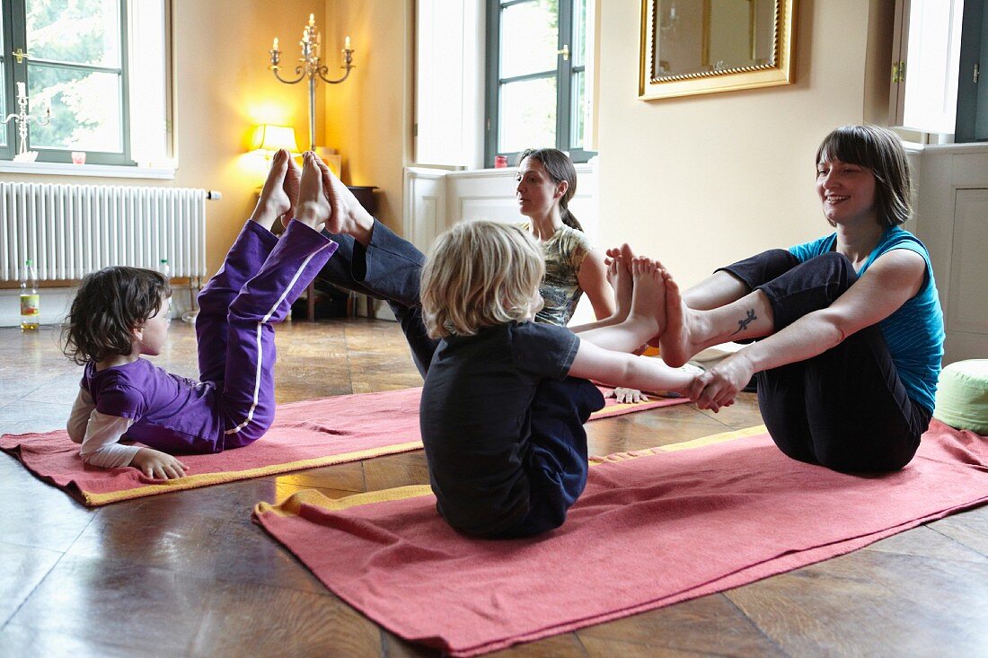 Mütter mit Kindern machen Yoga-Übungen