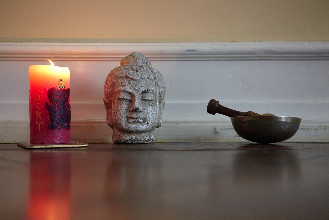 Kerze, Buddhakopf und Klangschale im Yoga-Übungsraum