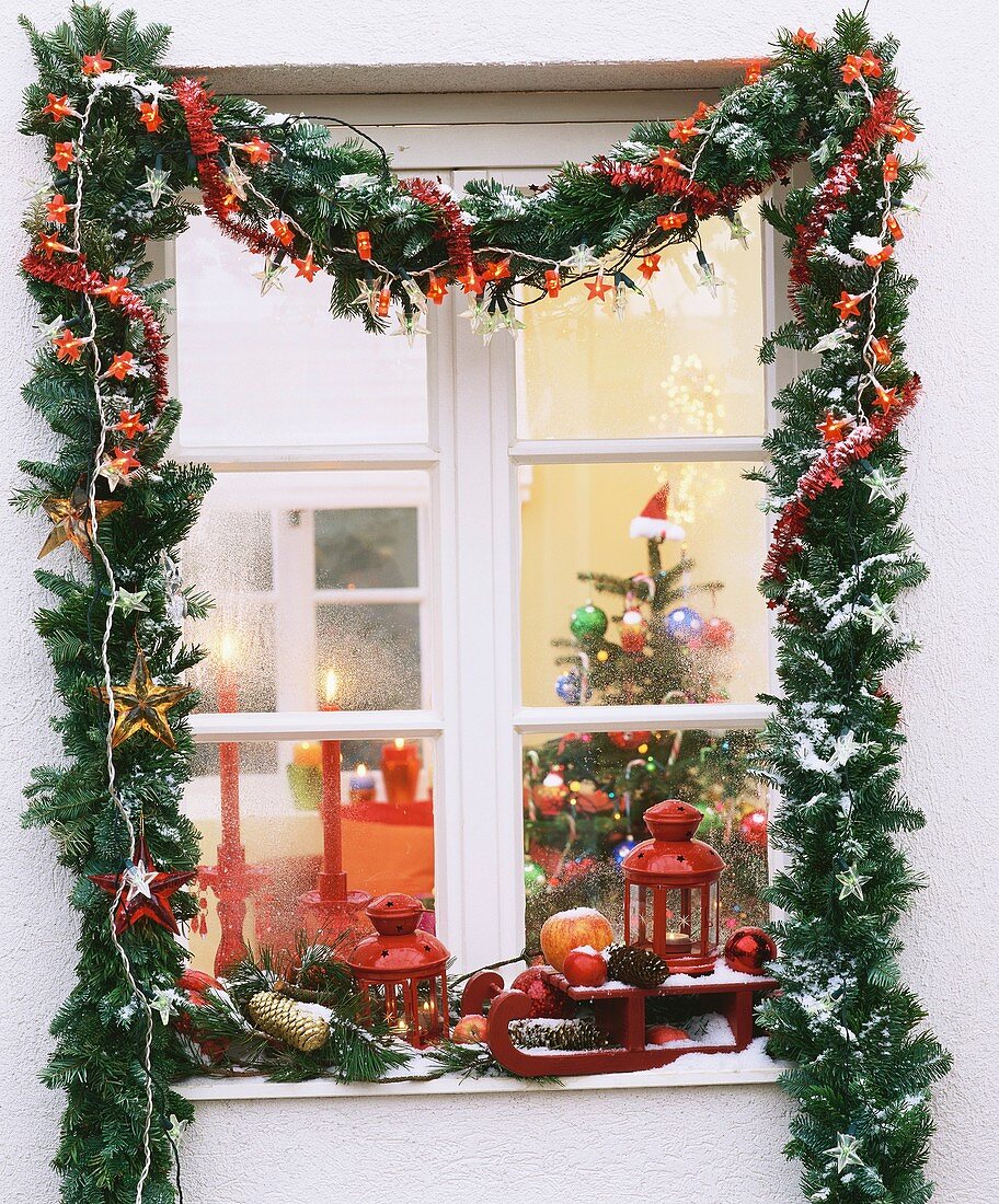 Christmas window with garland of greenery and fairy lights