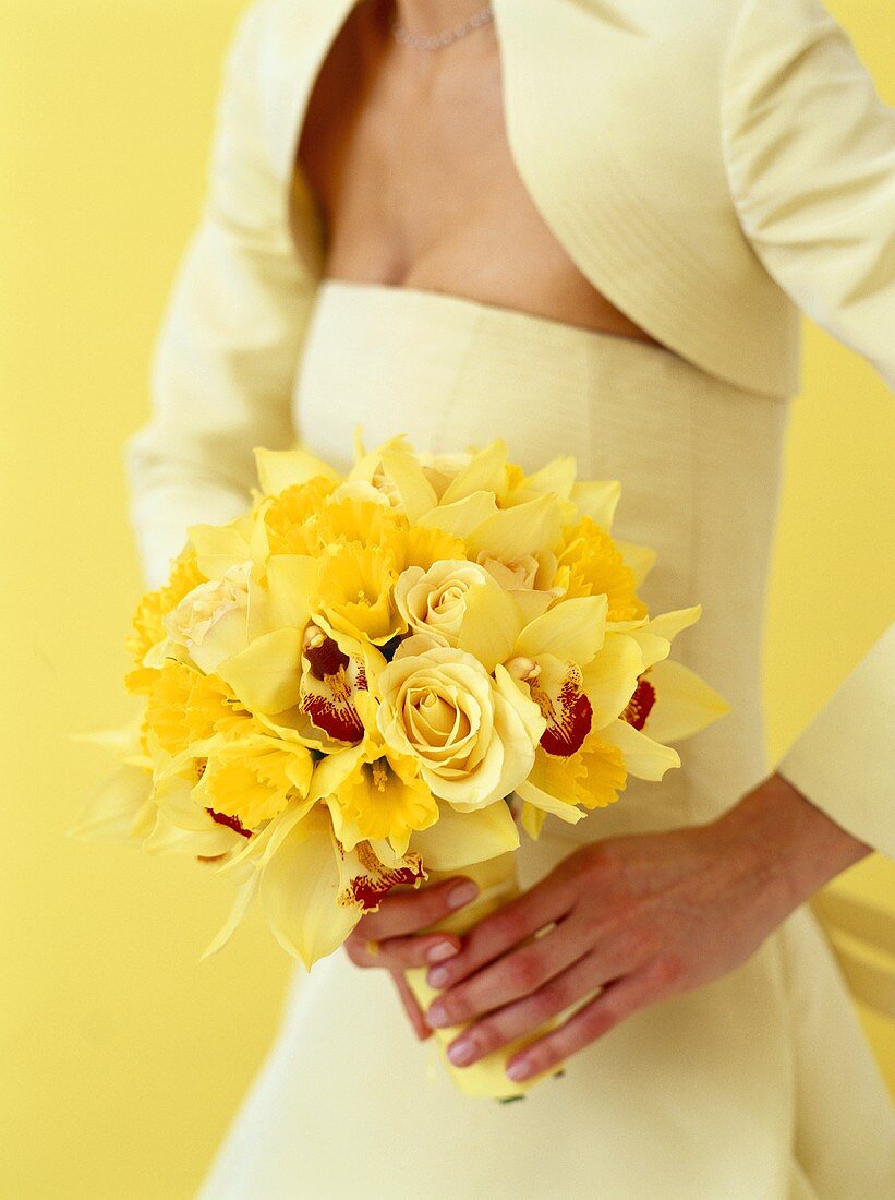 Braut hält Blumenstrauss aus gelben Rosen und Orchideen