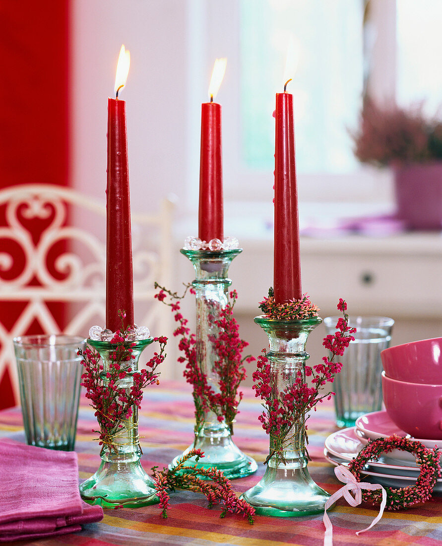 Glaskerzenleuchter mit roten Kerzen, dahinter Kaffeegeschirr