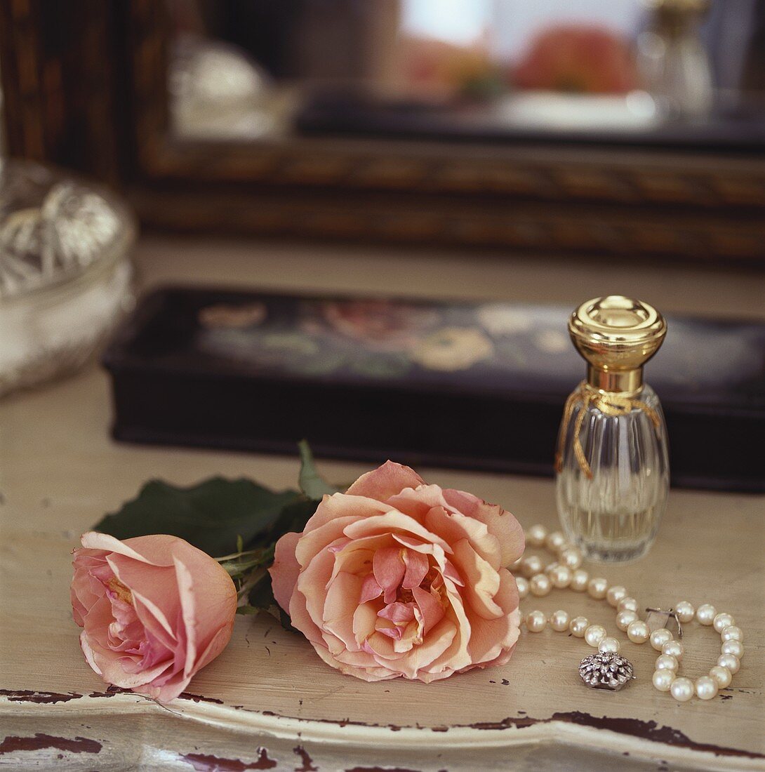 Rosen, Perlenkette und Parfümfläschchen