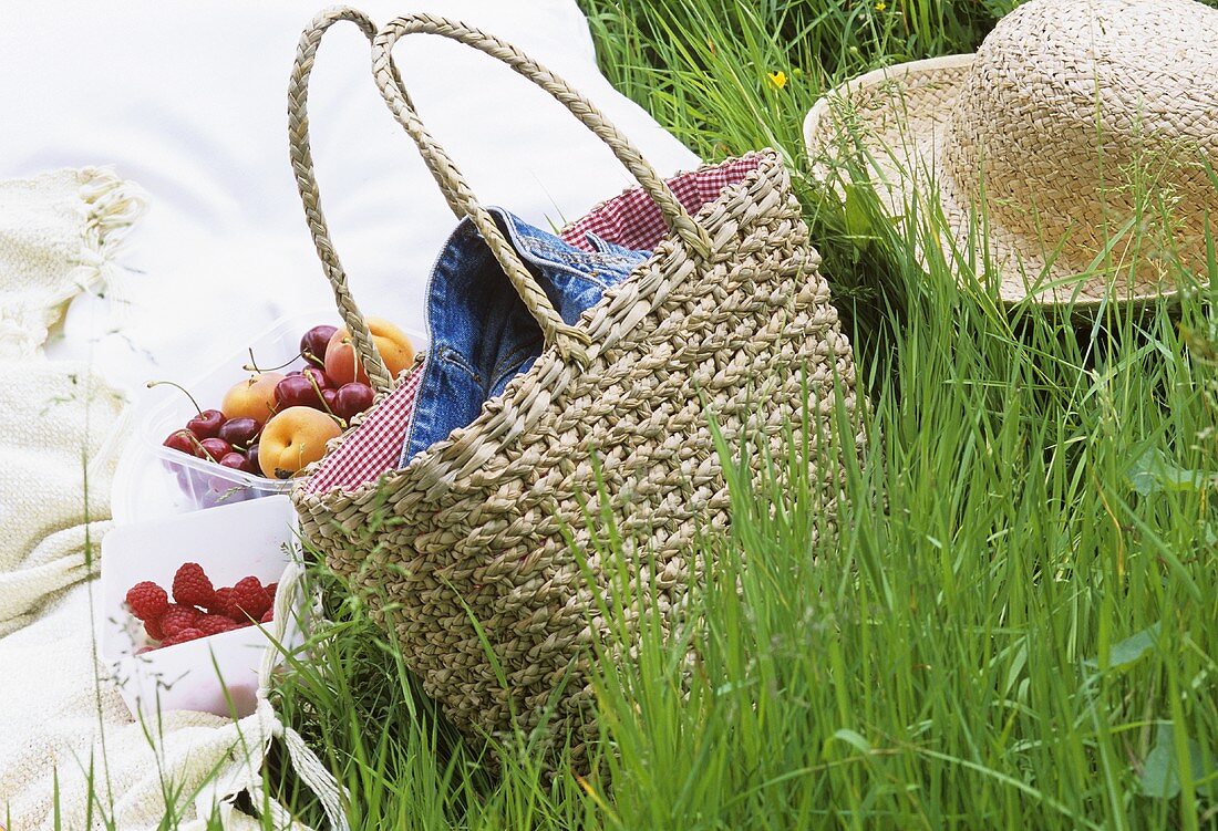 Fruit, basket and straw hat in grass