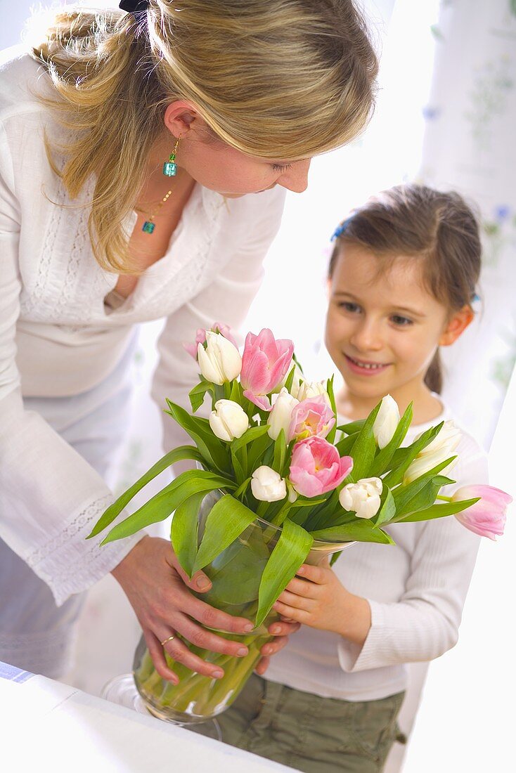 Woman and girl holding vase of tulips