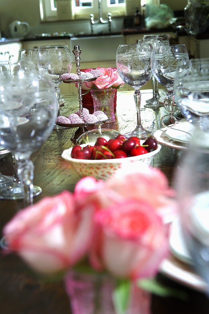 Gedeckter Tisch mit Rosendeko, Kirschen und Schokotalern