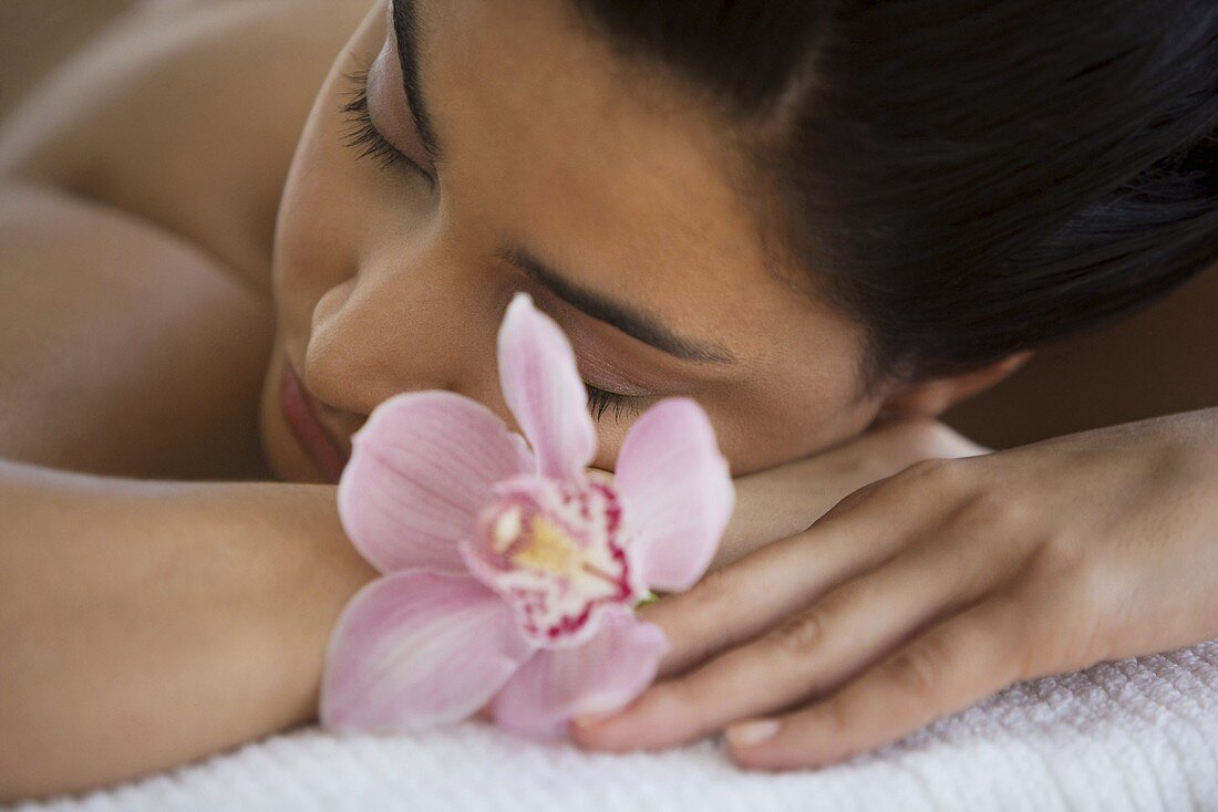 A young woman lying on a massage table with orchid flowers