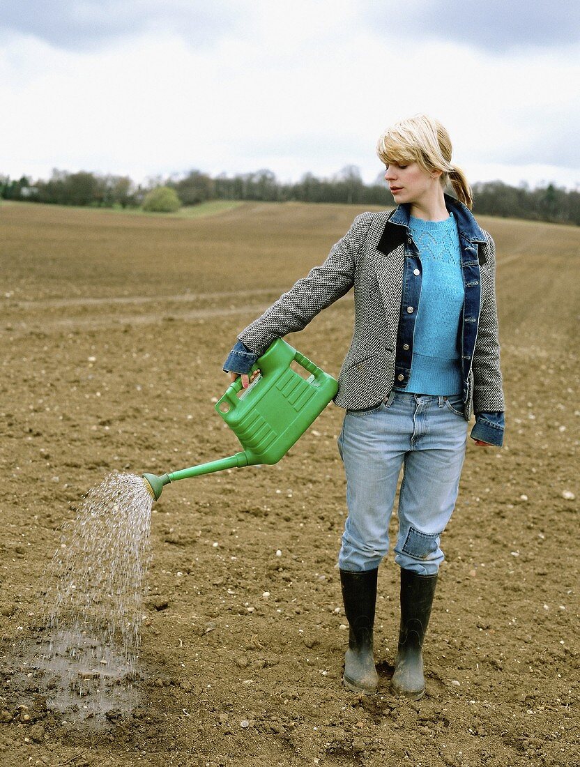 A woman watering a field with a watering can