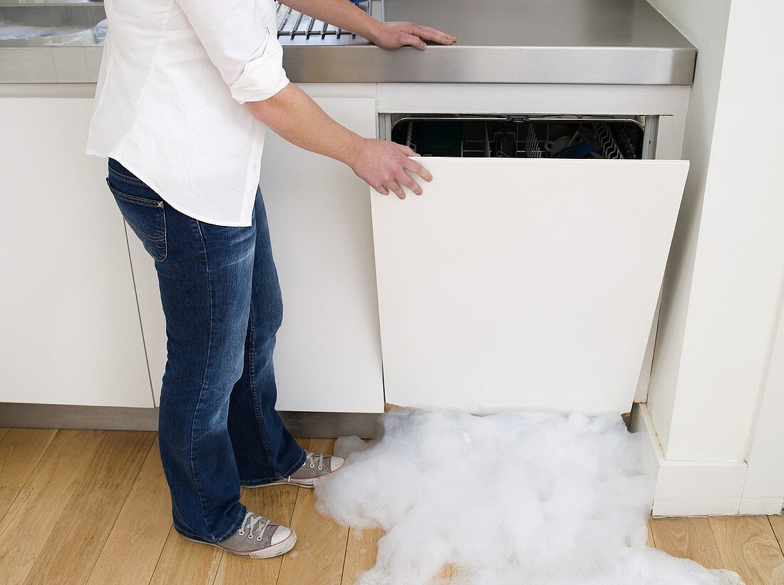 A woman opening a leaking dishwasher