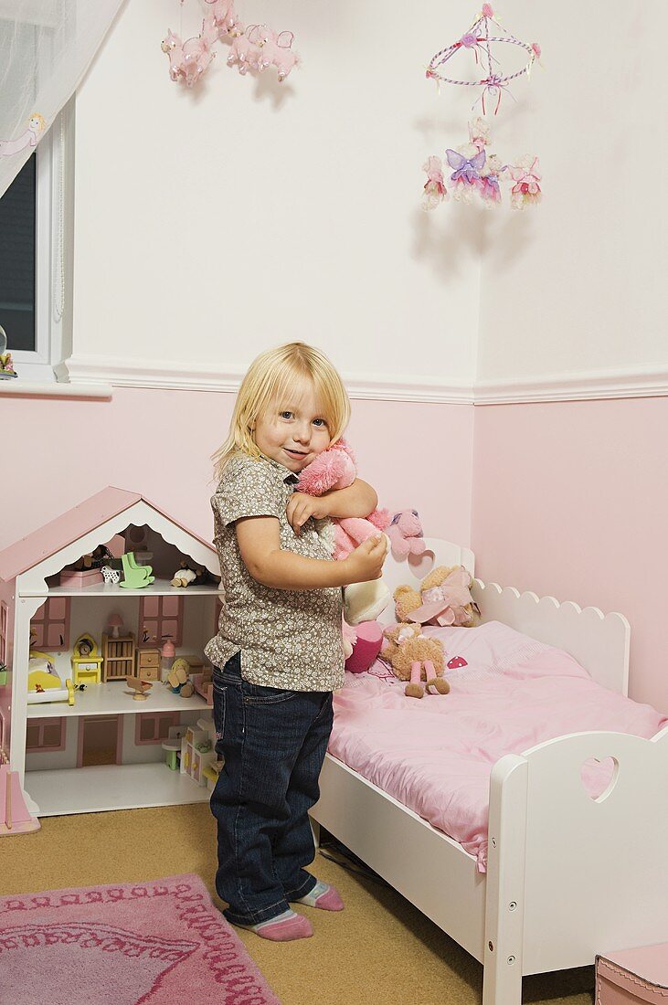 Kleines Mädchen mit Kuscheltier in roasfarbenem Kinderzimmer